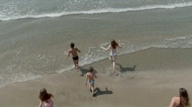 Deniz dalgalarına doğru koşan çocukların hava görüntüleri.