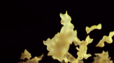 Pasta mafaldine flies up on black background
