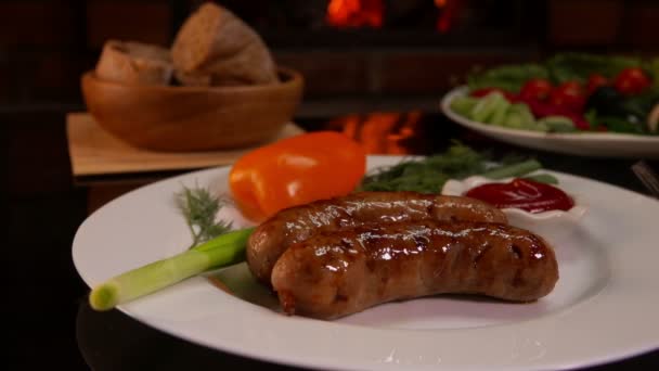 Plate with grilled sausages near burning fireplace — Stock Video