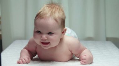 Sevimli bebek beyaz battaniyenin üstünde yatıyor.