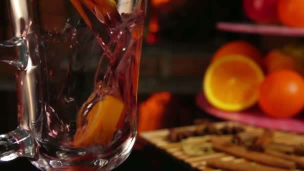 Glühwein met sinaasappels wordt in een glas gegoten — Stockvideo
