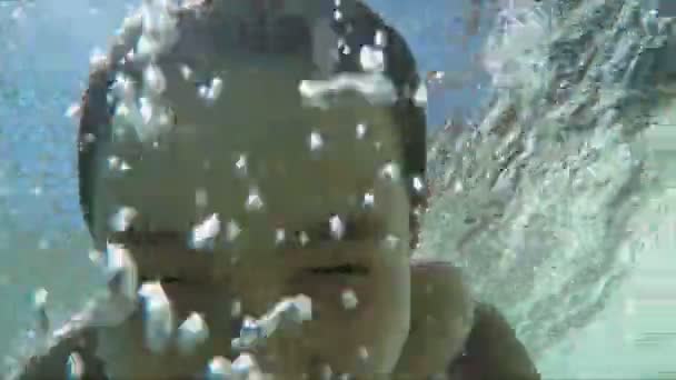 Счастливый мальчик плавает под водой и показывает знак мира — стоковое видео