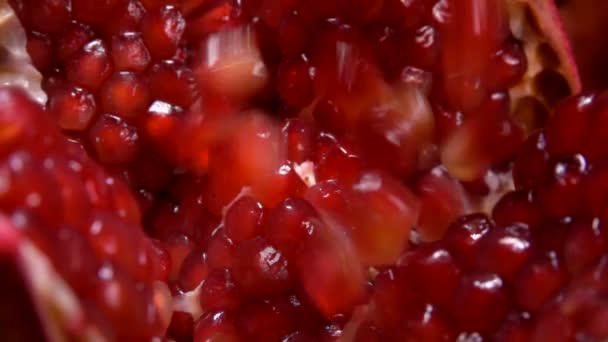 Graines de grenade rouge juteuses tombent sur un fruit coupé — Video