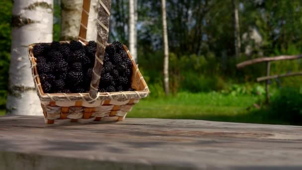 Brombeeren fallen aus einem Korb auf einen Holztisch — Stockvideo