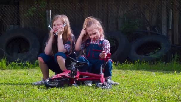 도구를 가지고 일하는 두 소녀는 자전거를 고칠 수없다 — 비디오