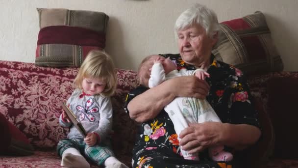 Abuela está meciendo pequeño bebé en sus brazos — Vídeos de Stock