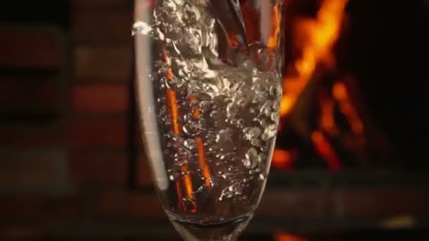 Шампанское наливается в стакан рядом с камином — стоковое видео