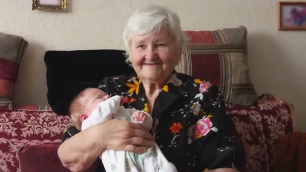 Vrouw geeft haar baby in de armen van grootmoeder — Stockvideo