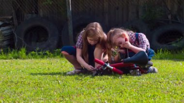 İki küçük kız bir bisikleti tamir ediyor.