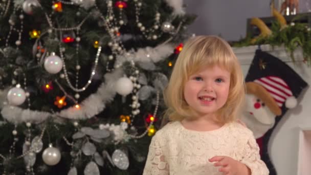 Schattig meisje op de achtergrond van kerstboom — Stockvideo