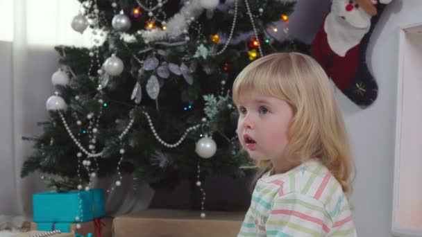 Маленькую девочку поражает рождественская подарочная коробка — стоковое видео