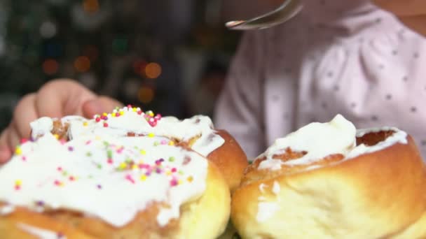 Hand kastar strössel på kanelbullar med grädde — Stockvideo