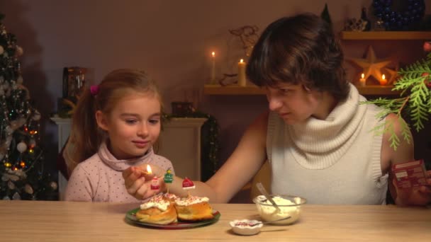 Moeder steekt kaars aan op de kaneelbroodjes. — Stockvideo