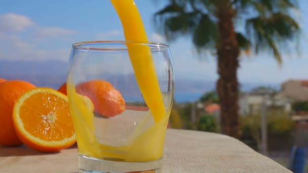 O suco de laranja fresco é derramado em um copo — Vídeo de Stock