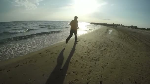 Gün batımında sahilde koşan bir adam. — Stok video