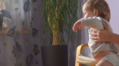 Anne bebeğinin ilk adımlarını atmasına yardım ediyor.