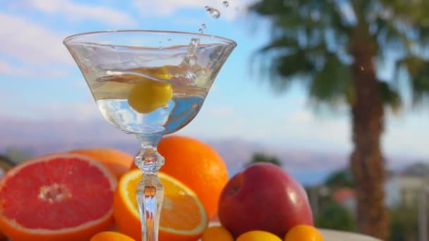 Olivy padají do martini vedle citrusových plodů — Stock video