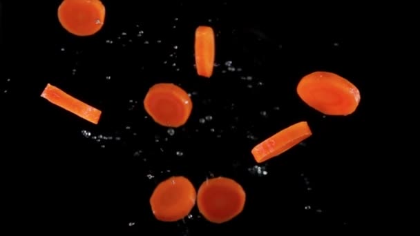 Cenouras picadas voando em um fundo preto — Vídeo de Stock