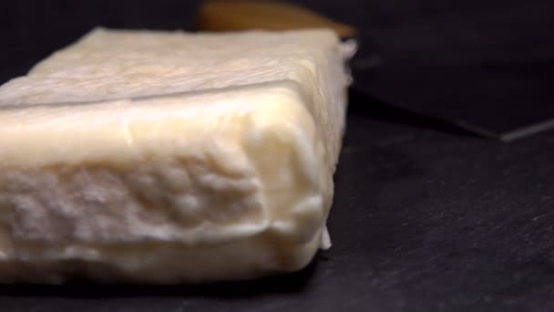 Couteau coupe un fromage à pâte molle sur un tableau noir — Video