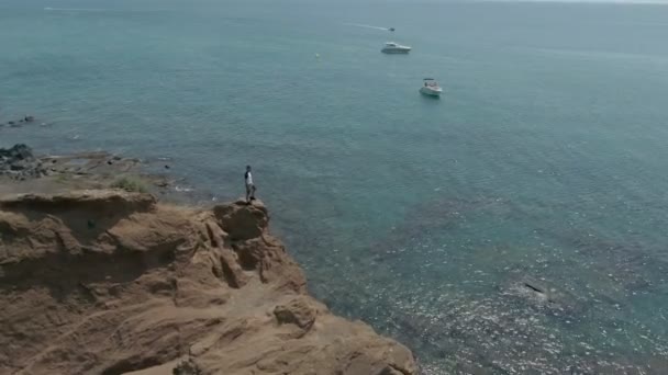 Aerial shot of a man standing above a clear sea — Stockvideo