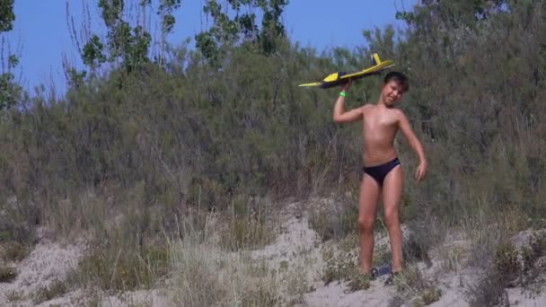 Jongen speelt met model van vliegtuig op het strand — Stockvideo