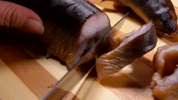 Primer plano de las manos cortando anguila ahumada en porciones — Vídeos de Stock