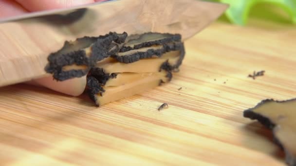 Hand cuts black truffle with a knife into a strips — Stock Video