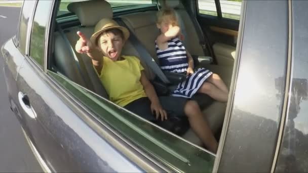 Boy and girl are riding at the backseat of car — Stockvideo