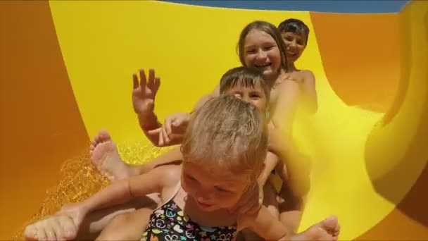 Niños felices montando un tobogán en un parque acuático — Vídeos de Stock