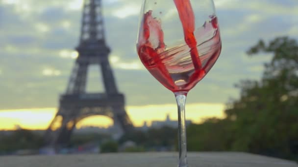 Czerwone wino wlewa się do szklanki w pobliżu Wieży Eiffla. — Wideo stockowe