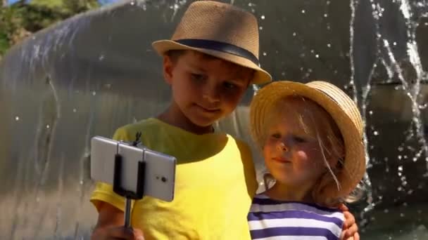 Маленький хлопчик і дівчинка в соломі роблять селфі — стокове відео