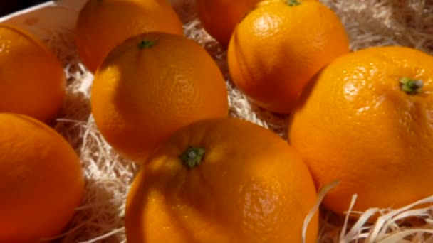 Рука берет спелый апельсин из деревянного ящика — стоковое видео