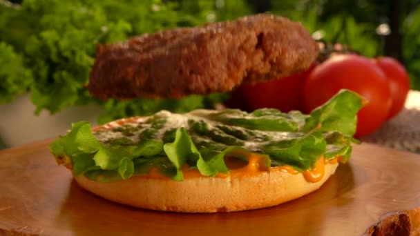 Толстая котлета падает на чизбургер. — стоковое видео