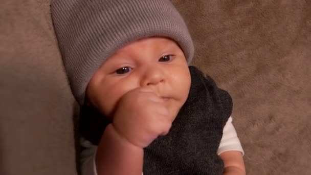 Kleine schattige baby in een grijze hoed niest — Stockvideo