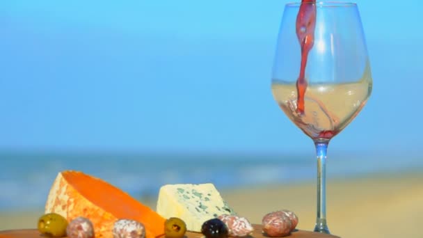 El vino tinto se vierte en un vaso junto a la tabla de quesos — Vídeo de stock