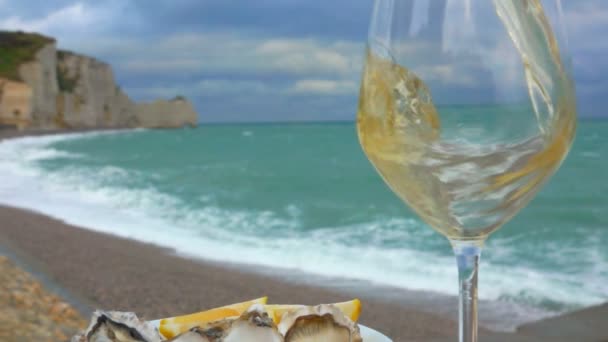 Vitt vin hälls i ett glas bredvid ostronen — Stockvideo