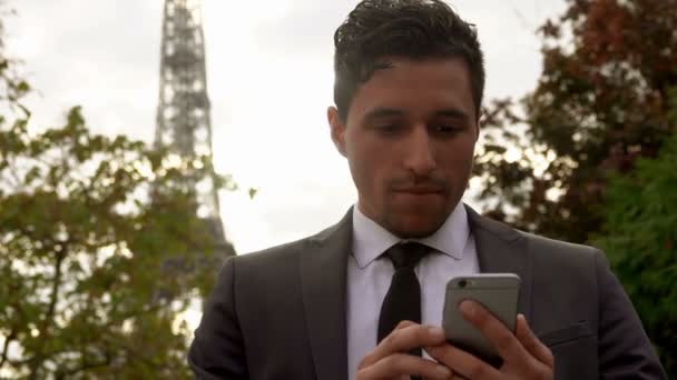 Man in black suit sends message on a cell phone 