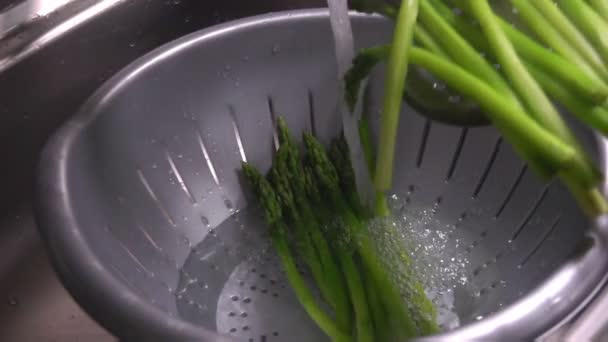 Lanzas de espárragos verdes hervidos caen en un agua fría — Vídeos de Stock