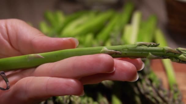 La mano está pelando espárragos verdes con un cuchillo especial — Vídeos de Stock