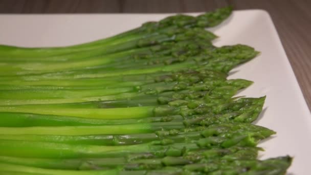 Green asparagus spears lying on a long white plate — 비디오