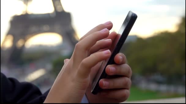 La mano hace clic en el teléfono junto a la Torre Eiffel — Vídeo de stock