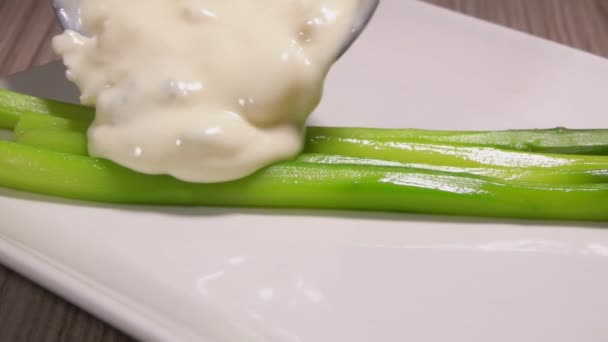 La salsa de queso se vierte en espárragos verdes hervidos — Vídeo de stock