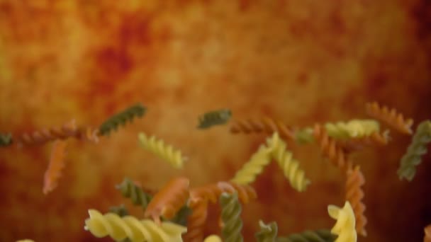 Gekleurde pasta fusili vliegen op een gele achtergrond — Stockvideo