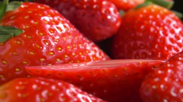 Trozo de fresas en rodajas cae sobre bayas rojas — Vídeo de stock