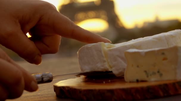 A kéz lágy brie sajtot visz az Eiffel-torony mellé. — Stock videók