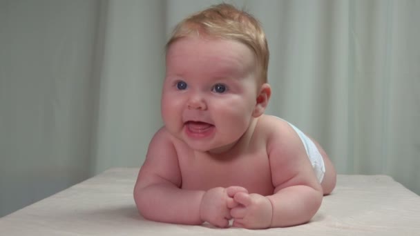 Barnet ligger på magen och ler glatt — Stockvideo