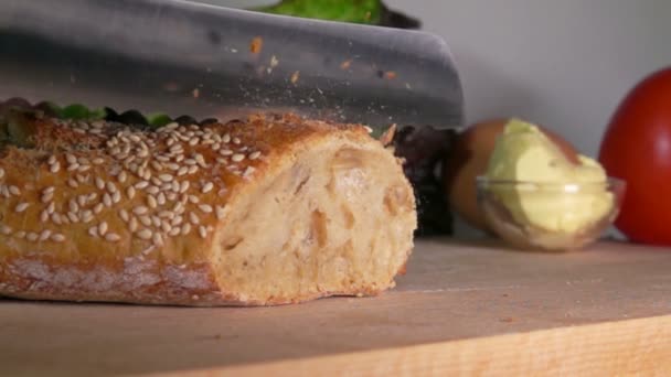 Baguette francesa con semillas de sésamo cortadas con un cuchillo — Vídeo de stock