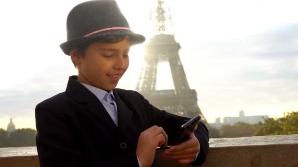 Menino bonito em um chapéu está olhando no telefone — Vídeo de Stock