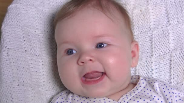 Slaperige baby met blauwe ogen liggend op een witte deken — Stockvideo