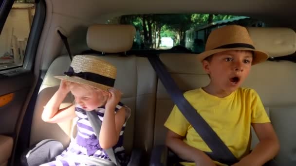 Un chico con sombrero bosteza en el asiento trasero del auto. — Vídeos de Stock